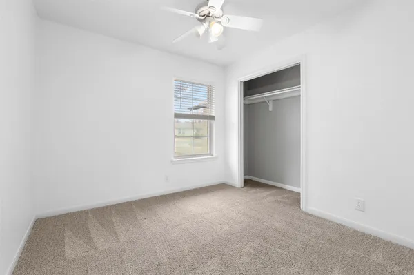 an empty room with a fan and a window