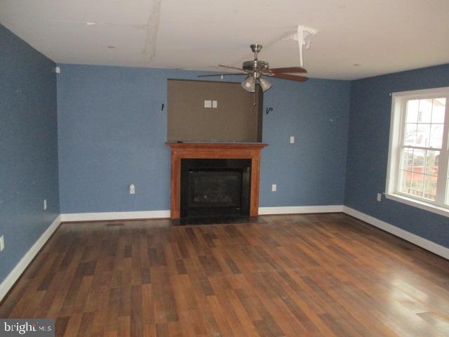 3102 Roger Road Baltimore, MD 21219 - Photo 4 of 16 an empty room with wooden floor a fireplace and windows