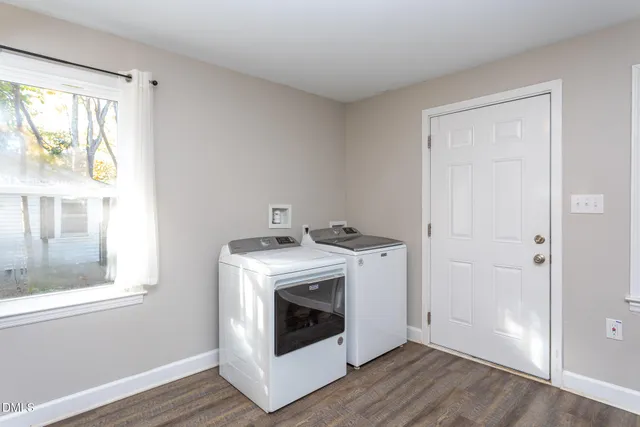 a utility room with wooden floor washer and dryer
