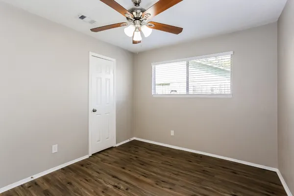 an empty room with wooden floor closet and windows