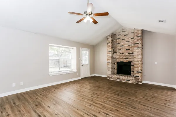 an empty room with windows a fireplace and a chandelier fan