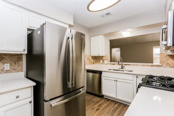 a kitchen with a refrigerator sink and white cabinets