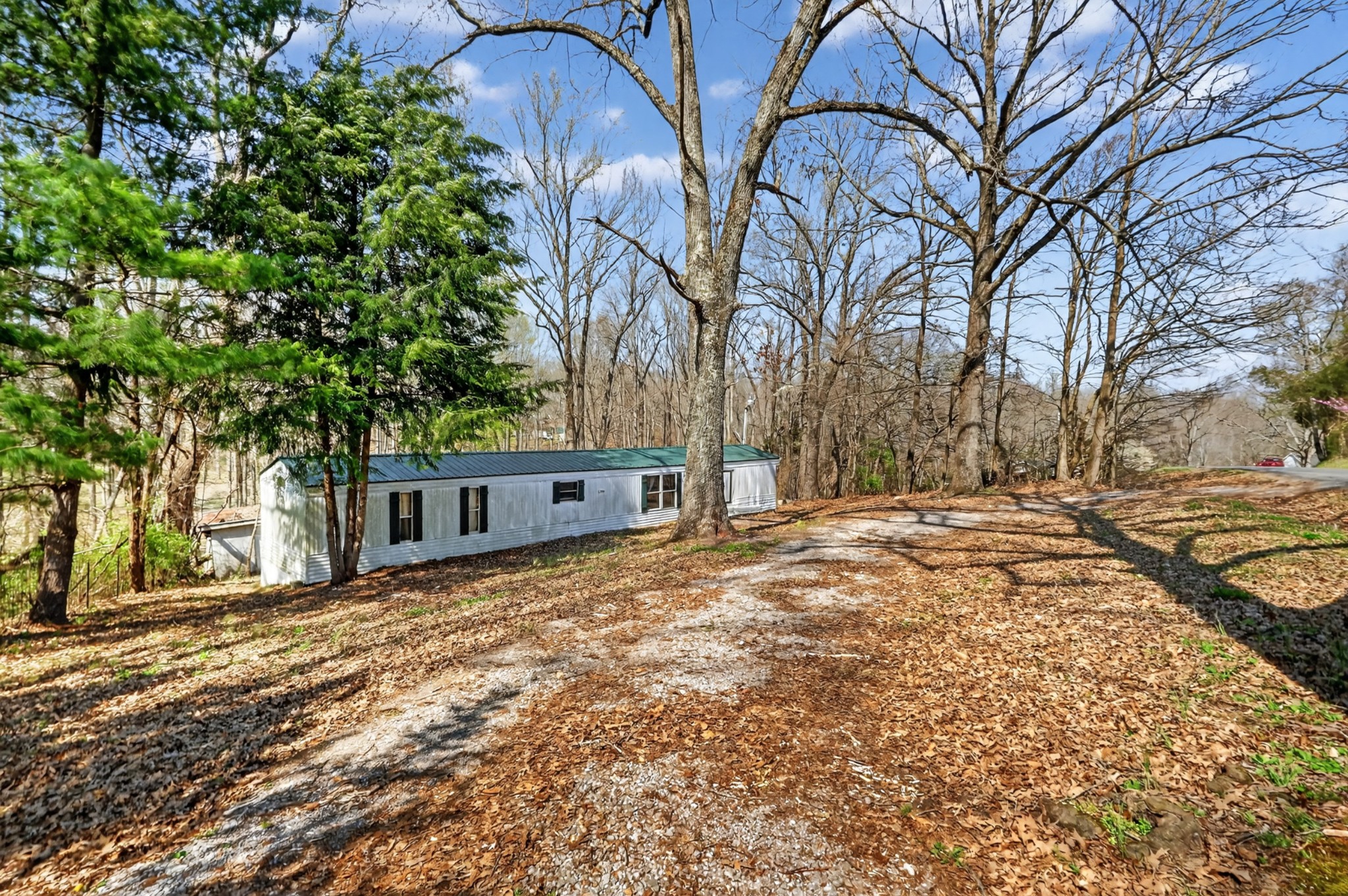 a backyard of a house with large trees and covered with wooden fence