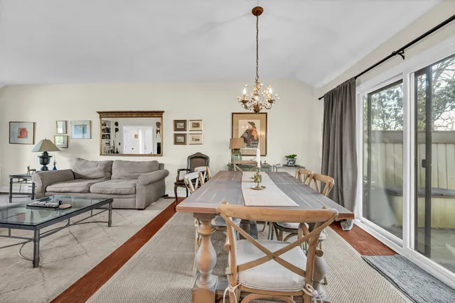 a view of a livingroom and dining room with furniture wooden floor a chandelier