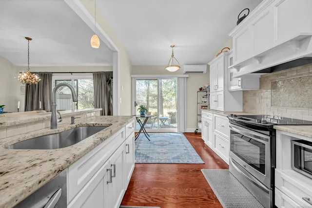 a large kitchen with granite countertop a sink and dishwasher a stove top oven with wooden floor