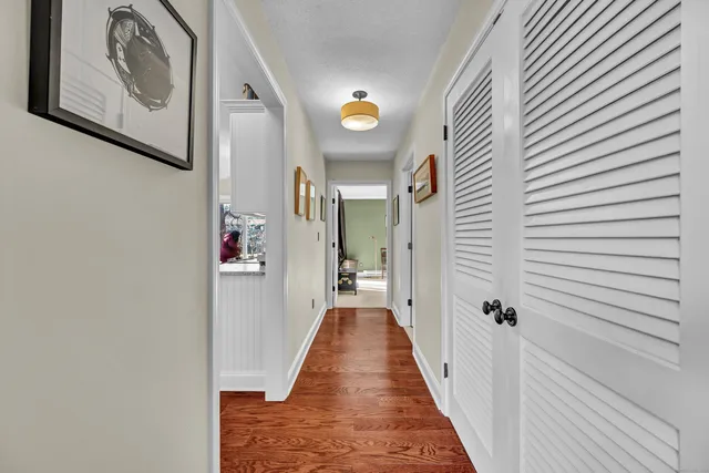 a view of a hallway with wooden floor and a bathroom