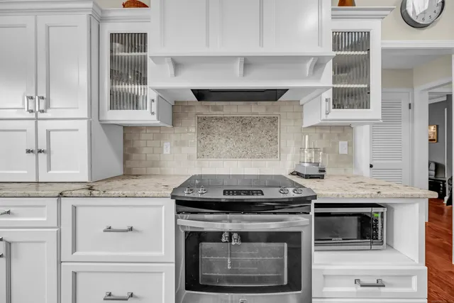 a kitchen with granite countertop a stove oven and white cabinets