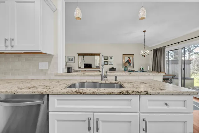 a bathroom with granite countertop white cabinets and a sink