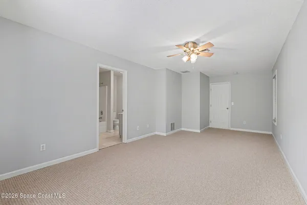 an empty room with chandelier fan and windows