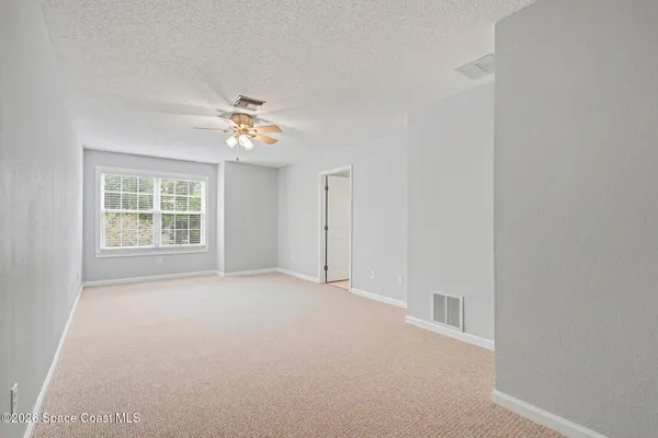 an empty room with a window and a ceiling fan