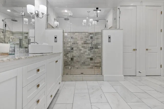 a bathroom with granite countertop white cabinets and a shower