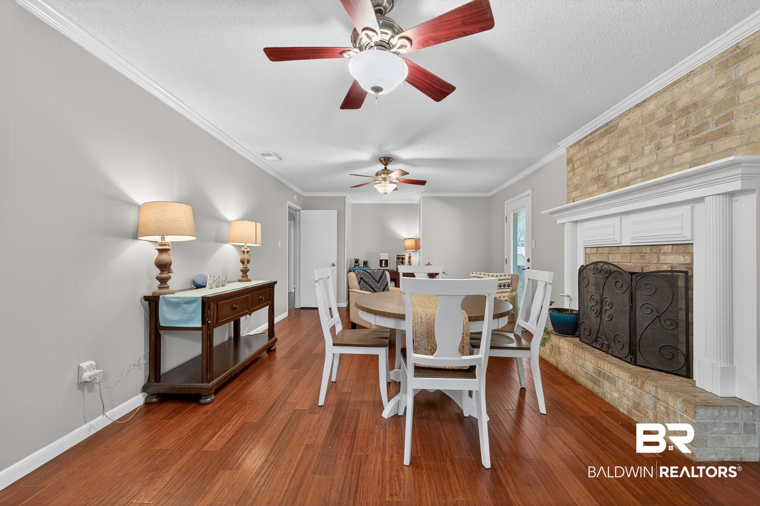46006 Pecan Lane Bay Minette, AL 36507 - Photo 15 of 40 Dining area featuring dark wood-style flooring, ornamental molding, ceiling fan, and a brick fireplace