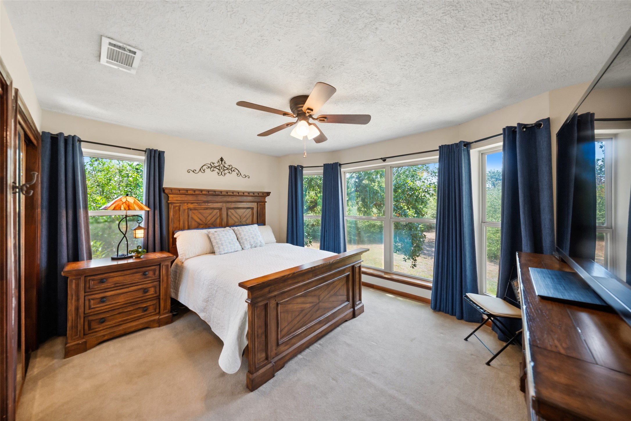 25948 Nelson Road Hempstead, TX 77445 - Photo 22 of 46 Spacious primary bedroom featuring hardwood flooring, ceiling fan, and large windows overlooking the surrounding greenery