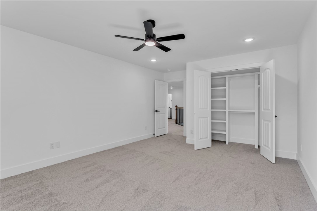 1723 Harris Bridge Road Anderson, SC 29621 - Photo 24 of 33 A well-lit bedroom with fresh carpeting, a modern ceiling fan, and built-in closet shelving.