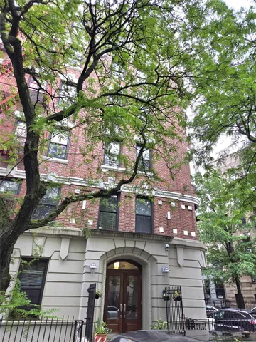 a front view of a house with large trees