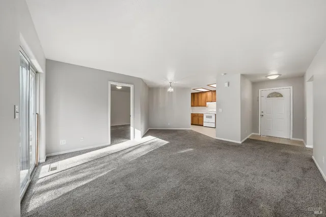 a view of an empty room with closet and kitchen