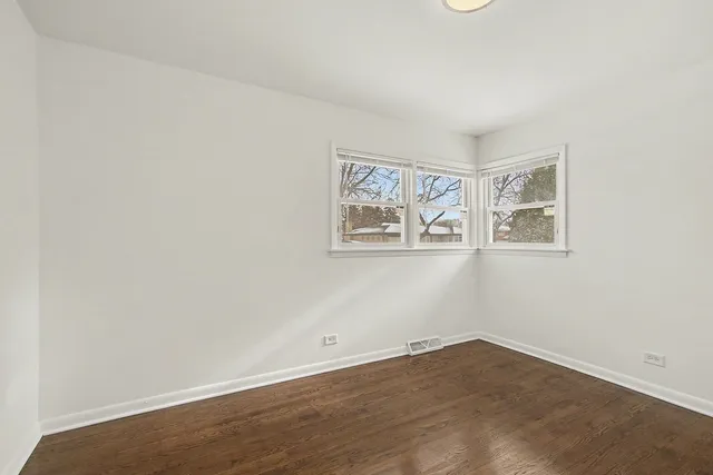 an empty room with wooden floor and window