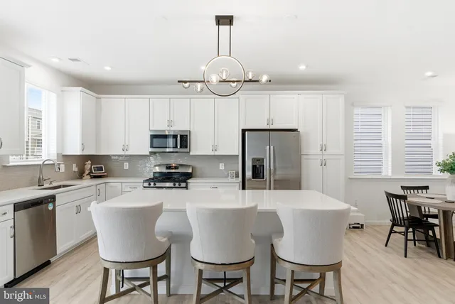 a kitchen with stainless steel appliances granite countertop a dining table chairs stove refrigerator and microwave