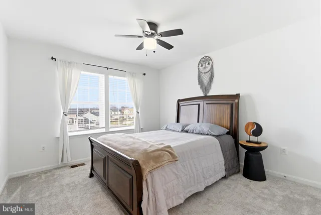 an empty room with chandelier fan and windows