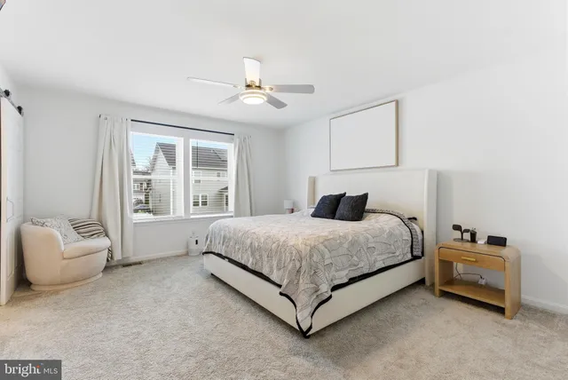 a bedroom with a bed a flat screen tv and a ceiling fan