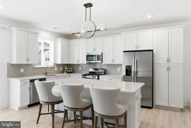 a kitchen with stainless steel appliances a dining table chairs microwave and sink