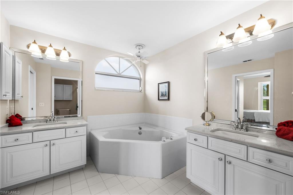 8015 Tiger Cove, Unit 204 Naples, FL 34113 - Photo 18 of 24 a bathroom with a tub a sink double vanity and a mirror