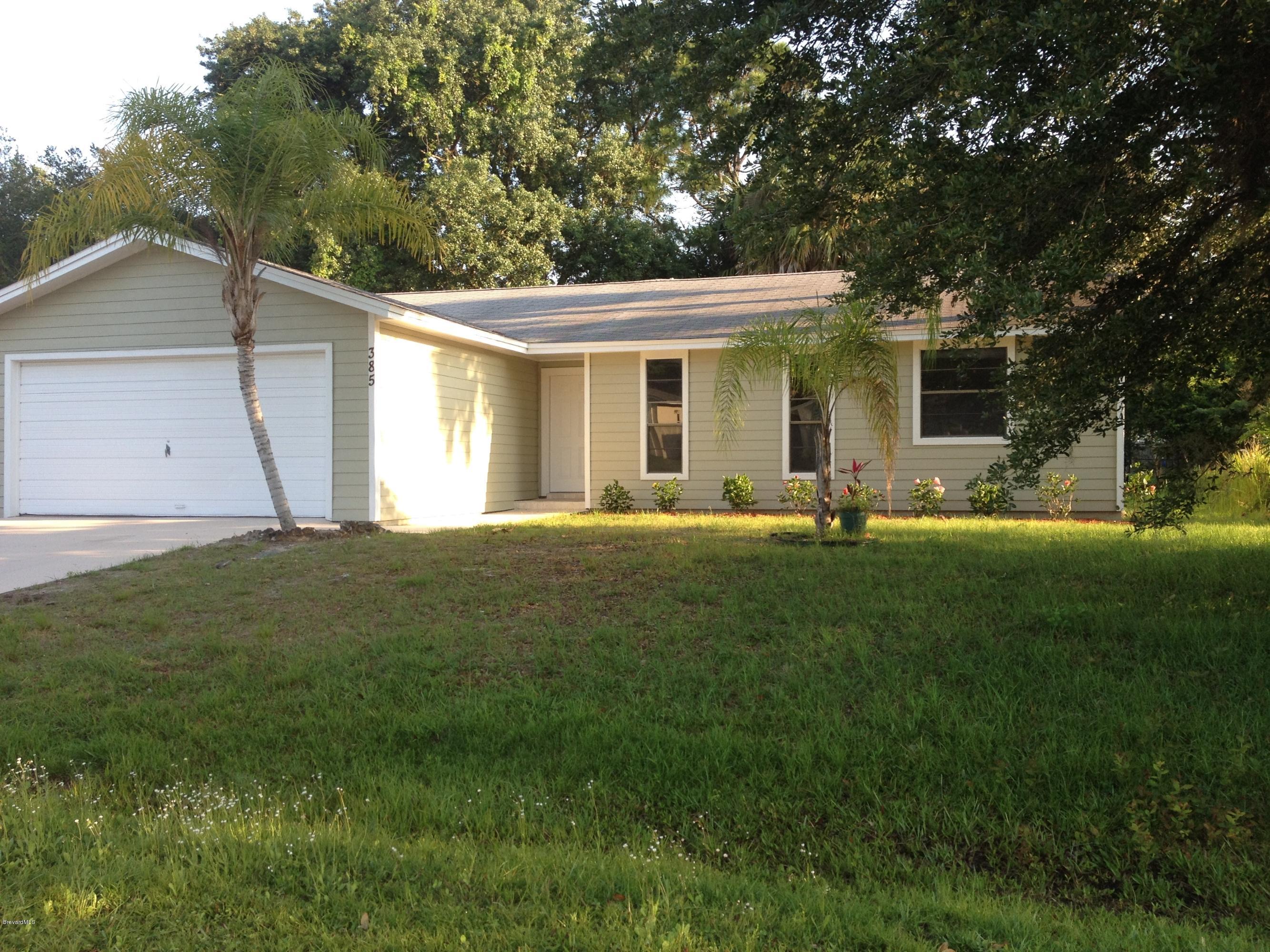 385 Rheine Road Northwest Palm Bay, FL 32907 - Photo 1 of 15 a front view of house with yard and green space