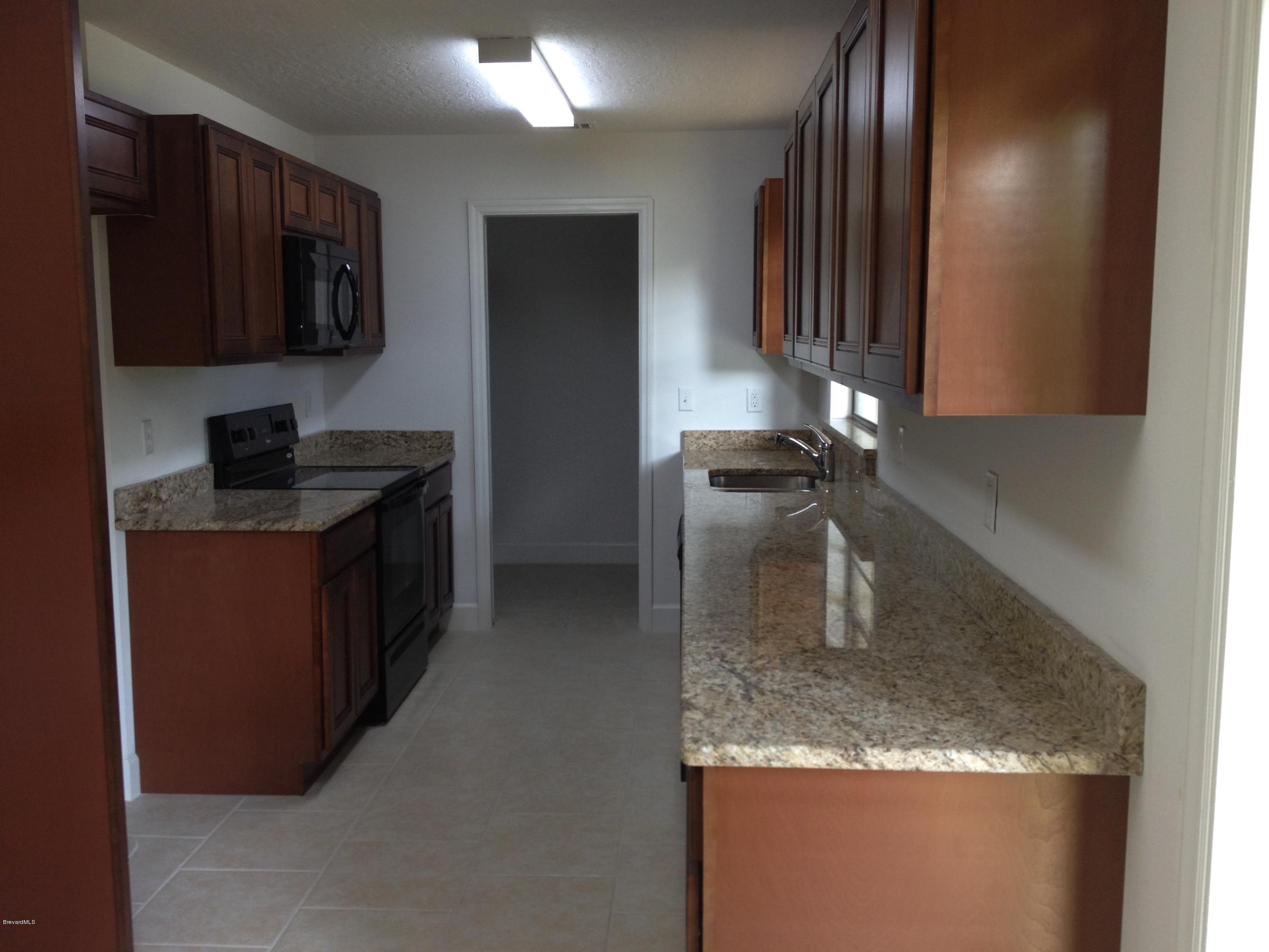 385 Rheine Road Northwest Palm Bay, FL 32907 - Photo 2 of 15 a kitchen with granite countertop a sink a stove and refrigerator