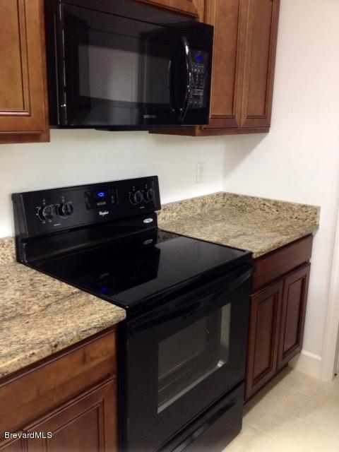 385 Rheine Road Northwest Palm Bay, FL 32907 - Photo 3 of 15 a kitchen with granite countertop a stove microwave and sink