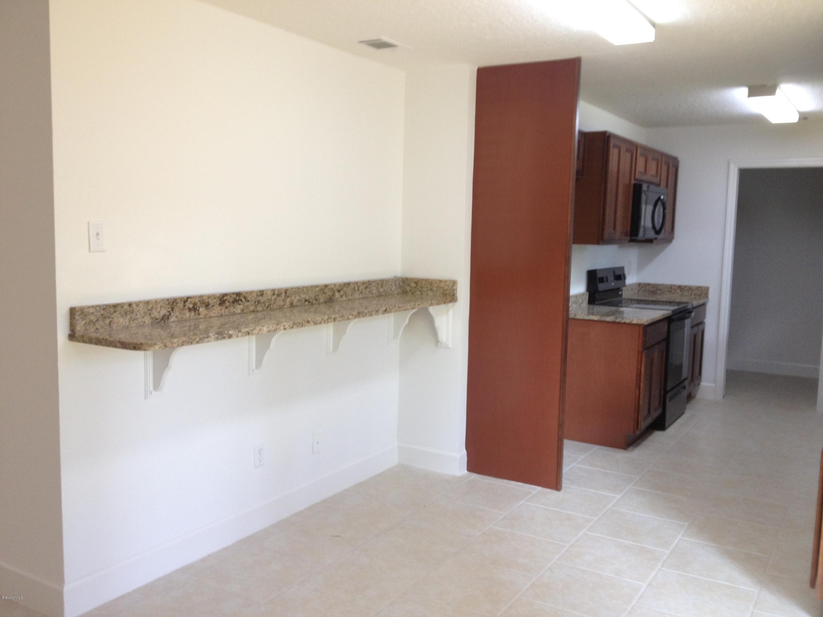 385 Rheine Road Northwest Palm Bay, FL 32907 - Photo 4 of 15 a view of a kitchen with stainless steel appliances granite countertop cabinets and a wooden floor