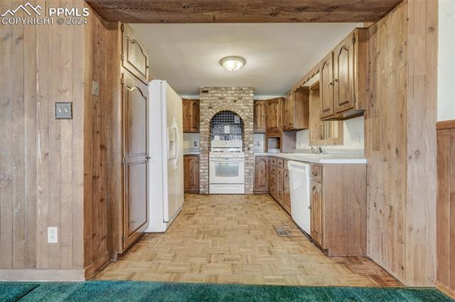 23555 Murphy Road Calhan, CO 80808 - Photo 20 of 49 Kitchen featuring light parquet flooring, white appliances, and wood walls