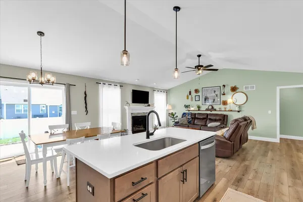 a kitchen with stainless steel appliances kitchen island granite countertop a dining table chairs and a refrigerator
