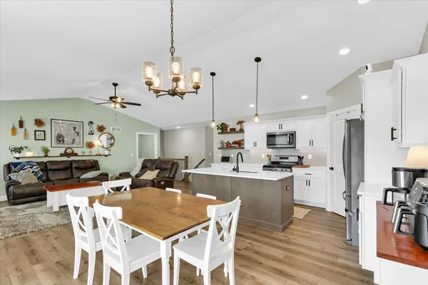a kitchen with stainless steel appliances kitchen island granite countertop a table chairs and a refrigerator