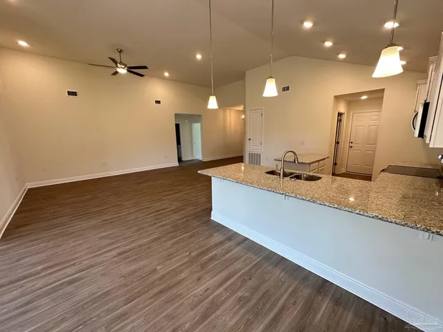 a large kitchen with stainless steel appliances a large counter top a refrigerator and a sink