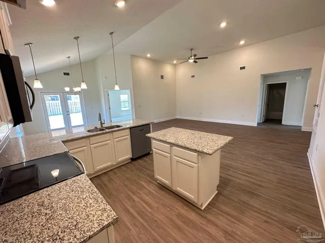 a kitchen with a sink and a stove top oven with wooden floor