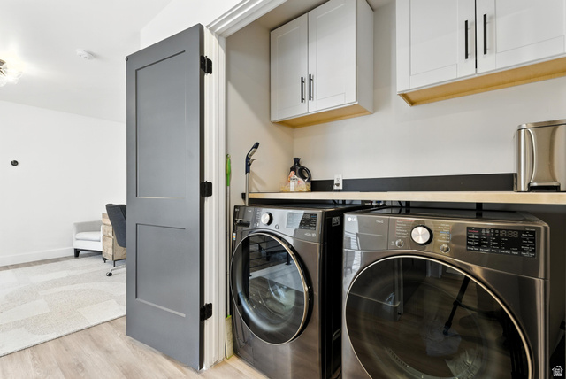 6039 North Westridge Road Heber City, UT 84032 - Photo 11 of 22 Dedicated laundry area featuring a front-loading washer and dryer, light wood-finish countertop, white upper cabinetry with black hardware, and wood-finish flooring