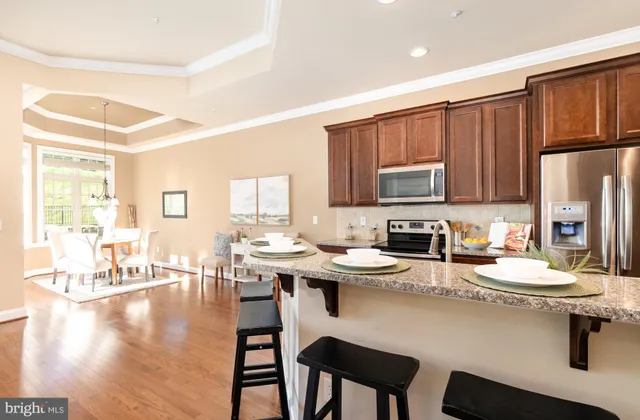 a kitchen with a refrigerator a stove a sink dishwasher with a dining table and chairs with wooden floor