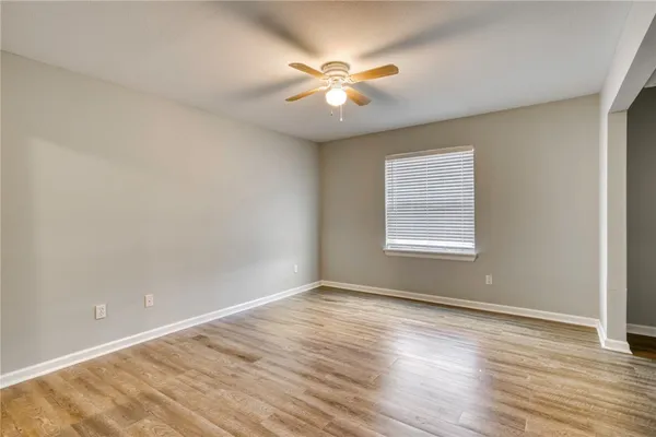 a view of an empty room with wooden floor and a window
