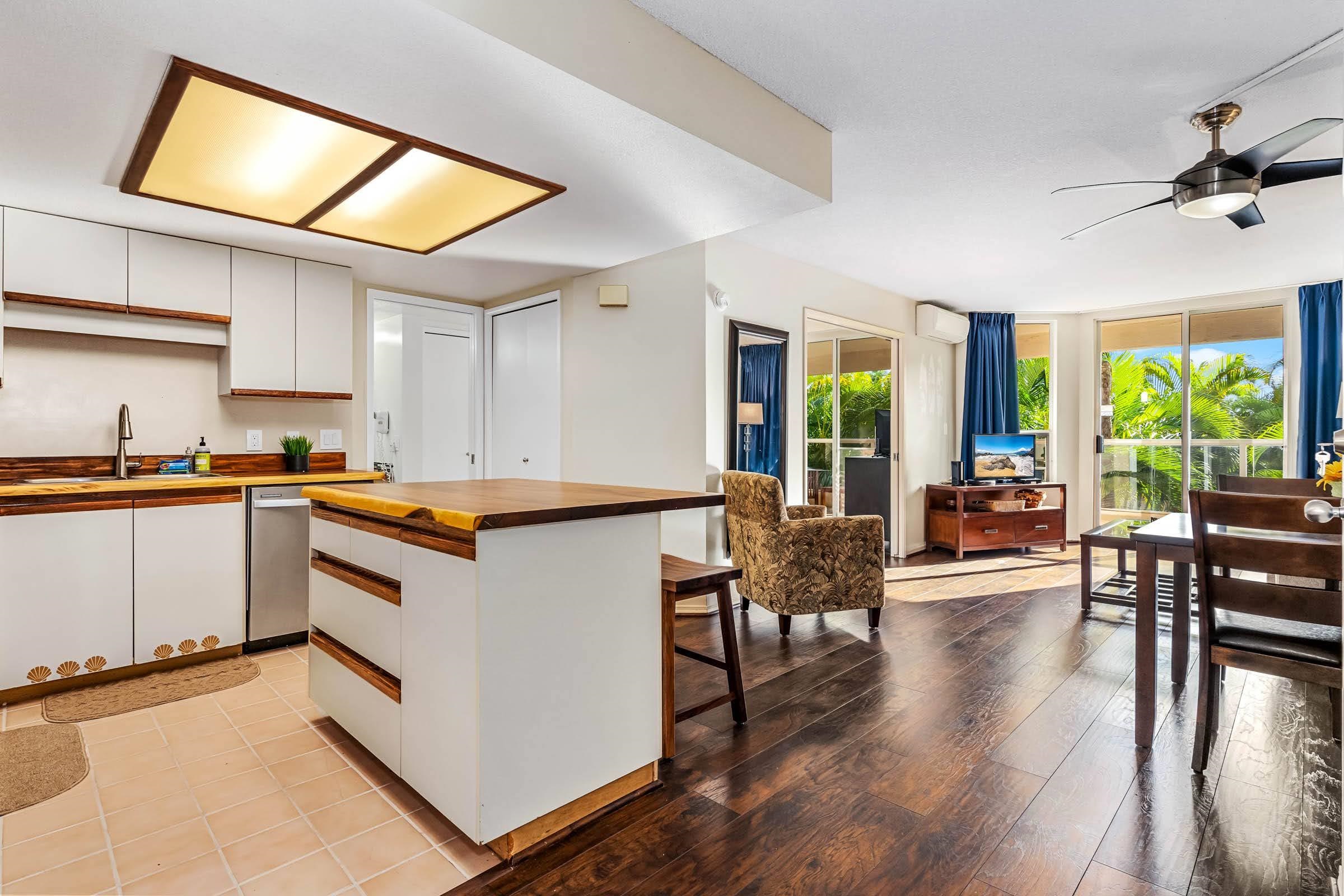 2575 South Kihei Road, Unit G209 Kihei, HI 96753 - Photo 2 of 27 a kitchen with stainless steel appliances granite countertop a stove top oven a sink a dining table and chairs with wooden floor