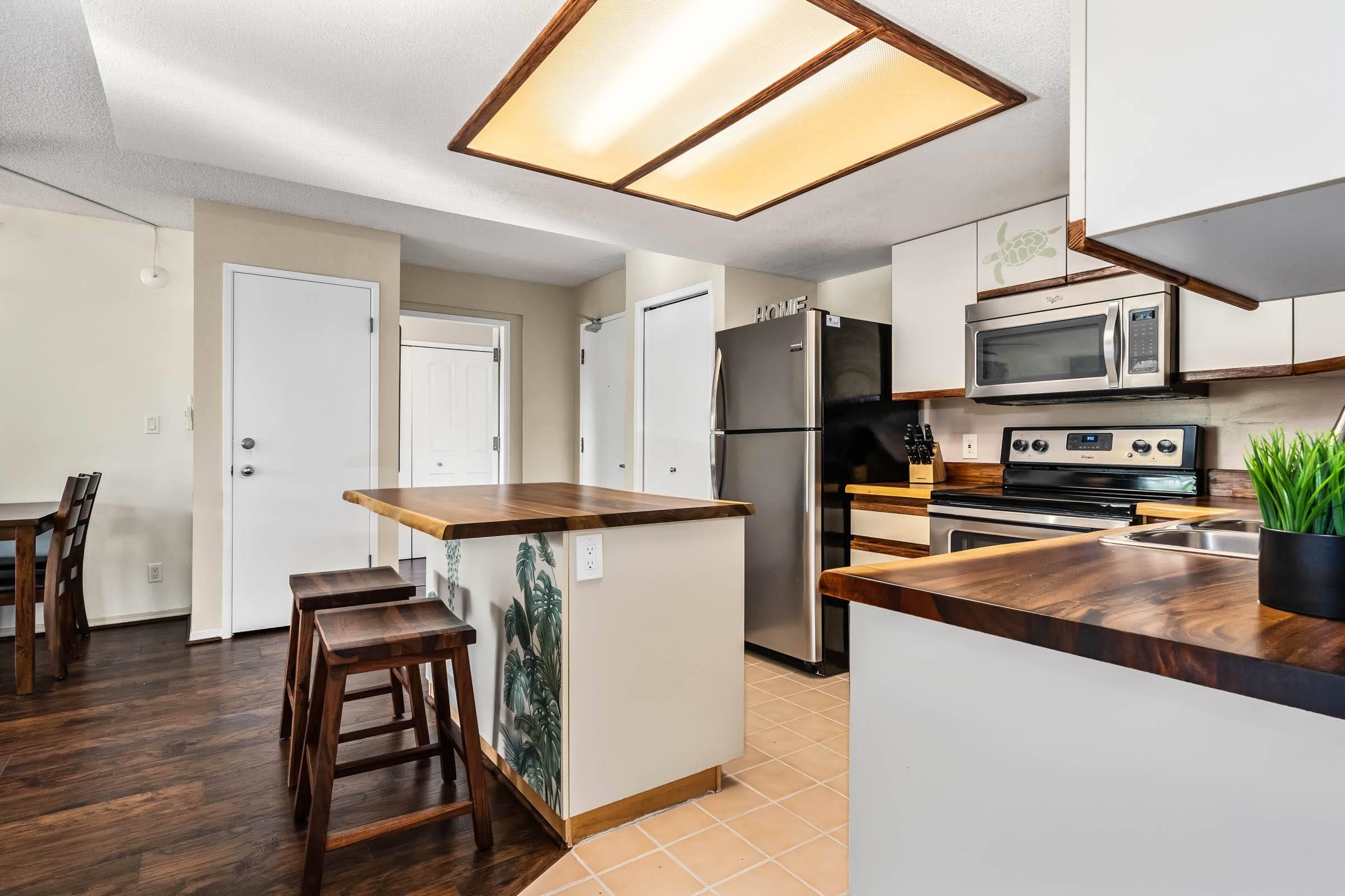 2575 South Kihei Road, Unit G209 Kihei, HI 96753 - Photo 8 of 27 a kitchen with stainless steel appliances granite countertop a stove refrigerator and a microwave oven with wooden floor