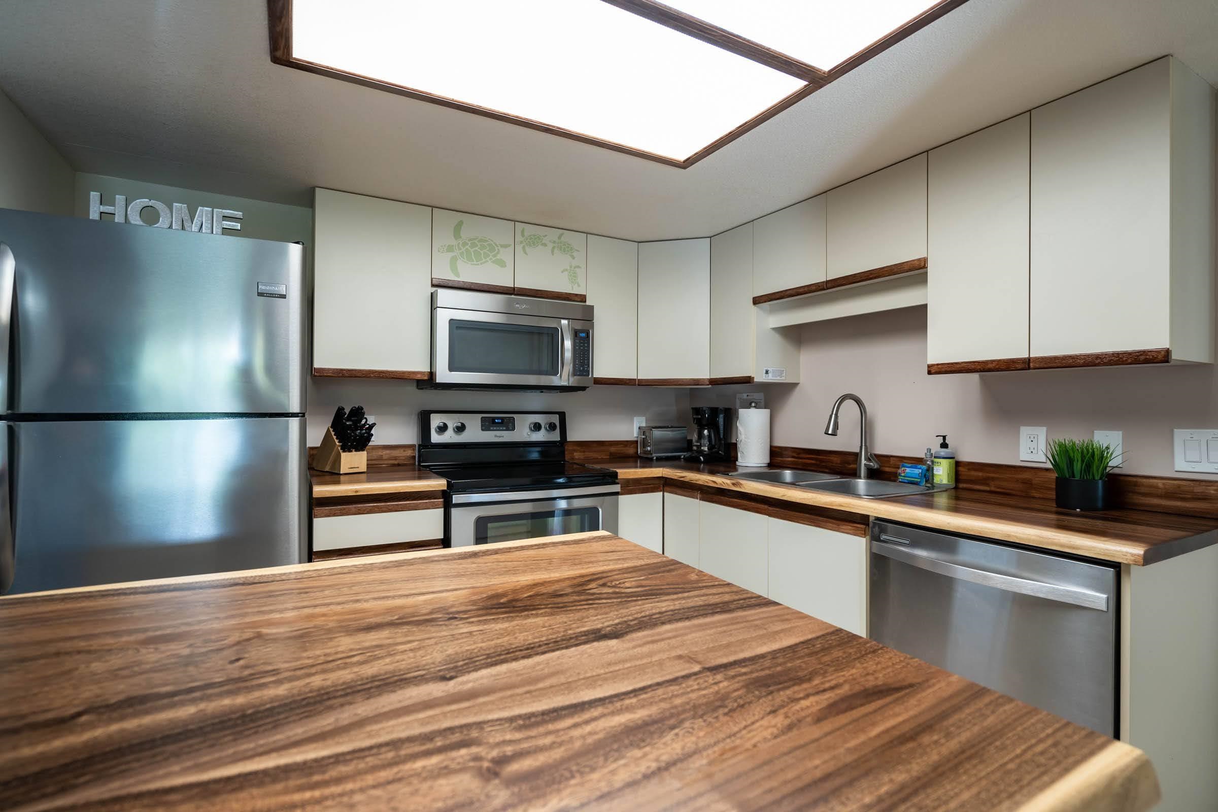 2575 South Kihei Road, Unit G209 Kihei, HI 96753 - Photo 9 of 27 a kitchen with granite countertop a refrigerator stove top oven and sink with wooden floor