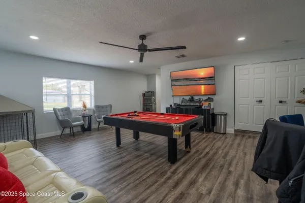 a room with furniture pool table flat screen tv and windows