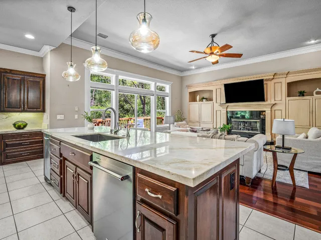 a kitchen with kitchen island granite countertop a stove a sink a dining table and chairs with wooden floor