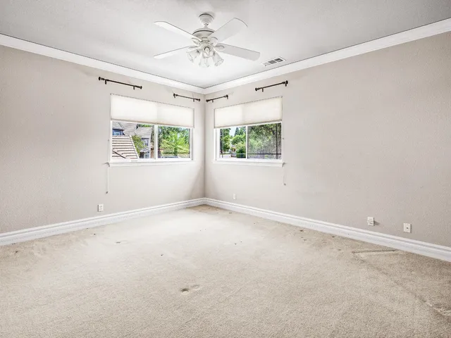 an empty room with windows and ceiling fan