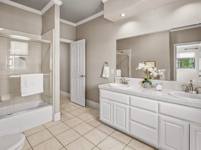 a bathroom with a double vanity sink mirror and bathtub