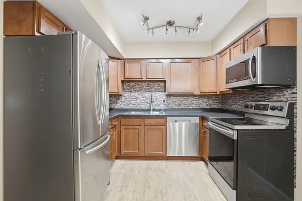 a kitchen with stainless steel appliances granite countertop a stove a sink and a refrigerator