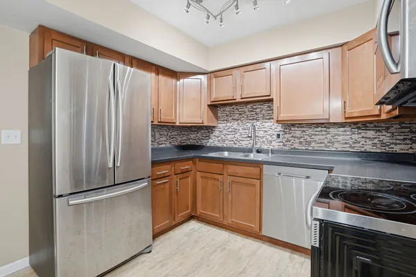 a kitchen with stainless steel appliances granite countertop a refrigerator a sink and white cabinets