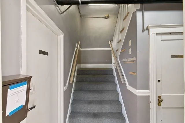 a view of staircase with lots of frames on wall and wooden floor