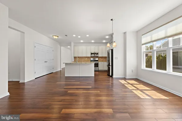 a view of kitchen with granite countertop refrigerator oven sink and white cabinets with wooden floor