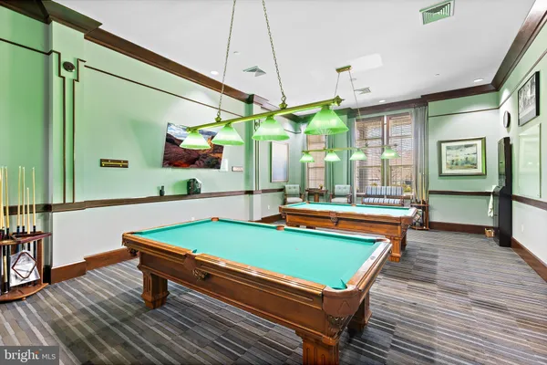 a room with wooden floor pool table and chairs
